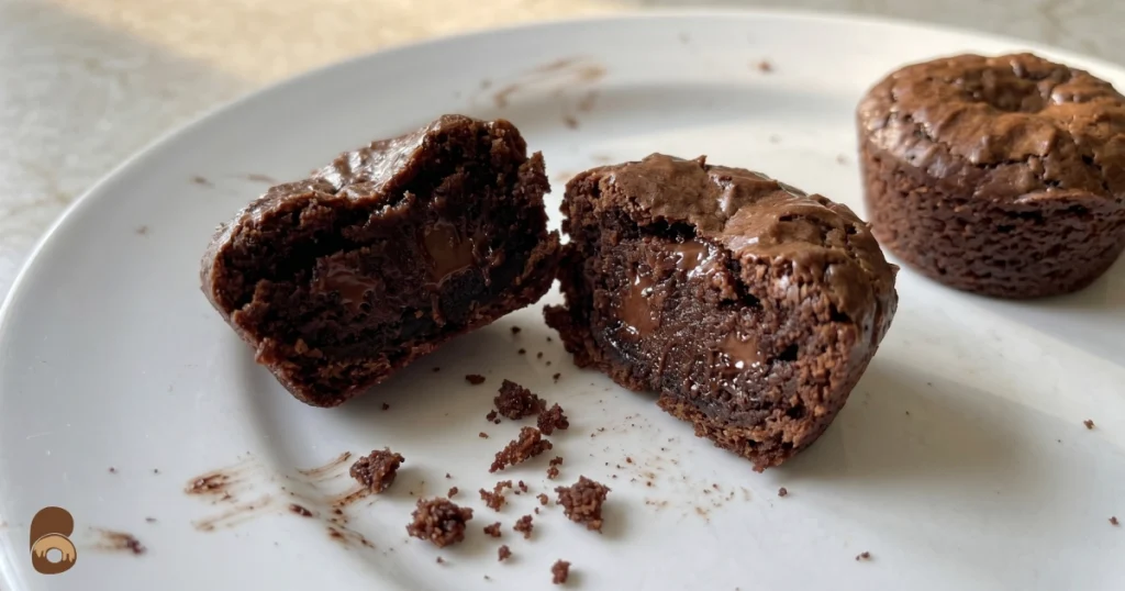 interior of two bite brownies broken in half showing fudgy moist crumb and chocolate chips